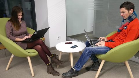 A young couple communicate with each other using a computer. Positive freelancers dressed in hipsters fashion clothes are working on a new promising project for their business.