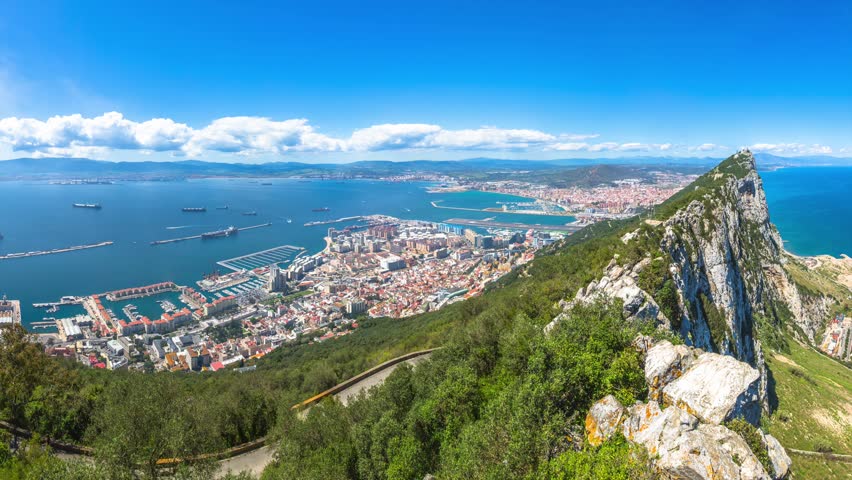 Panorama of top of Gibraltar Rock, in Upper Rock Natural Reserve: on the left Gibraltar town and bay, La Linea town in Spain at the far end, Mediterranean Sea on the right. United Kingdom, Europe.