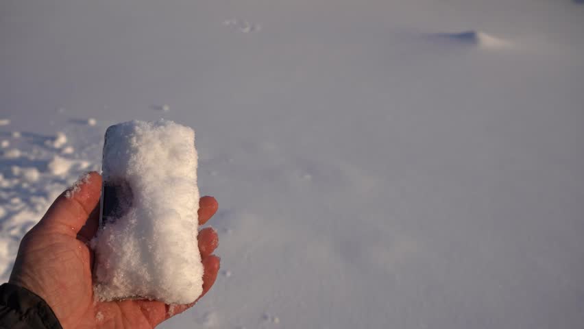 Snowy smart phone in mens hand in the winter time