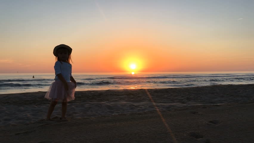 Little girl runs on the beach and laugh.