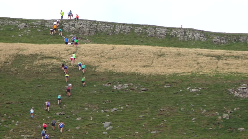 Fell race at the muker show 2018 showing runners reaching the top of a very steep hill.
