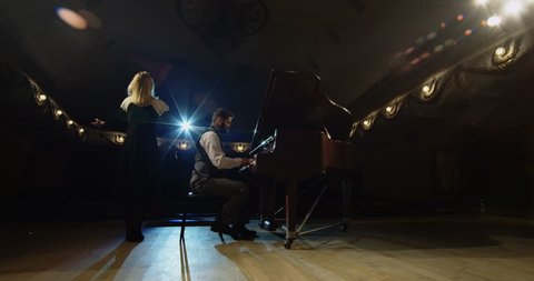 Medium shot of a woman singing while a man playing piano on the stage