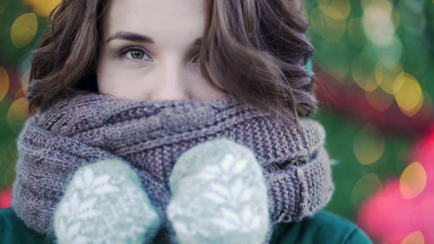 Winter portrait of a young beautiful girl on the streets of a European city. Close-up of beautiful young woman with scarf outside in winter. Model wearing coat, scarf