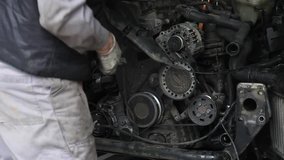 A damaged car at a car mechanic store, a car mechanic disassembling a car piece by piece