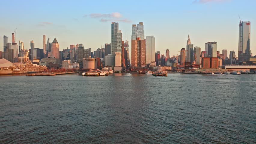 Aerial drone footage of New York skyline. The camera takes off from Hudson River and lifts up, towards the 42nd street canyon. Royalty-Free Stock Footage #1021680058