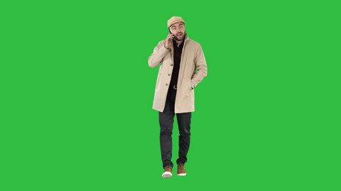 Man in trench coat walking and talking on the phone on a Green Screen, Chroma Key.
