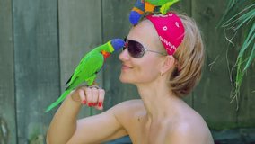young woman visiting natural park, with curious colorful parrots on her head and hand