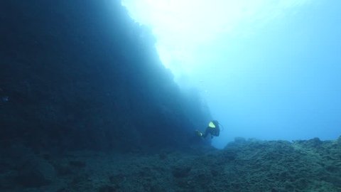 scuba divers underwater enjoying dive with sun shine sun beams and sun rays underwater rocks ocean scenery