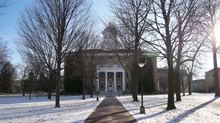 A building at Lawrence University in Appleton, Wisconsin during the winter time with a flag waving on top.