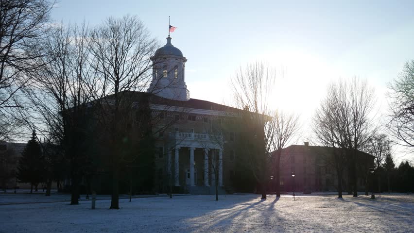 A building at Lawrence University in Appleton, Wisconsin during the winter time with a flag waving on top.