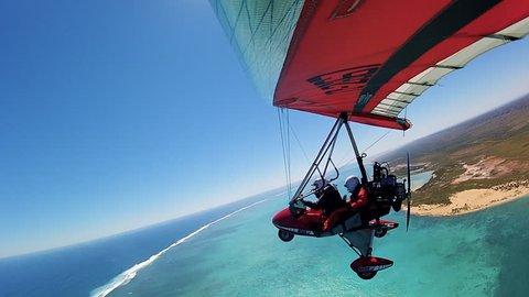 Wideshot of two hang gliders flying over coastal land and ocean