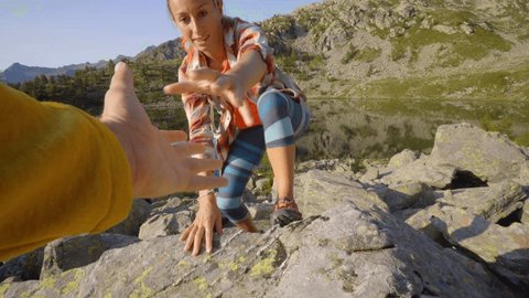 Teammate helping hiker to reach summit. Couple hiking in Switzerland, hand reach out to help female hiker reach the summit. A helping hand concept 