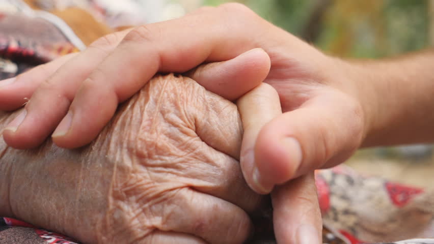 Close up of young male hand comforting an elderly arms of old woman outdoor. Grandson and grandmother spending time together outside. Concept of care and love. Side view Slow motion Royalty-Free Stock Footage #1021719619