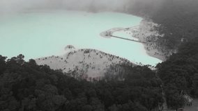 Ungraded aerial view clip through a thick fog of a volcanic crater known as Kawah Putih or White Crater, a sulphuric crater lake south of Bandung in West Java in Indonesia.