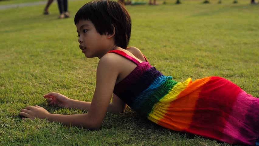 Girl rolling down on the field. Child plays on the low slope hill by rolling down
