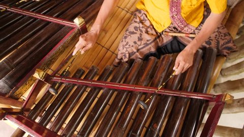 Traditional Balinese Music Instument Gamelan. Asian Musician Man in Traditional Clothes Playing on Bamboo Xylophone at Ceremony in Temple. 4K. Bali, Indonesia.