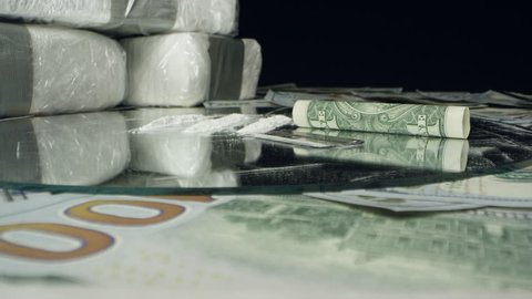 Moving over money and drugs on table top viewing lines and bricks of cocaine and 100 dollar bills.