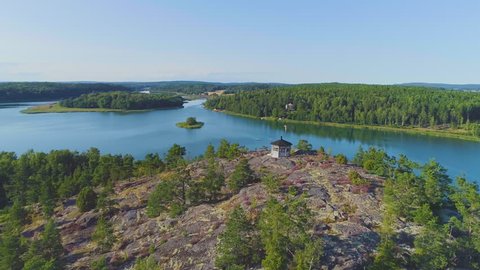 Cinematic aerial opening over rocky hills onto calm sea bay with boats. Scenic nature in Åland Islands, Finalnd with small fishing boats in the middle of the sea
