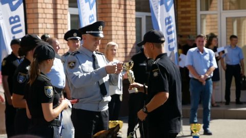 DNIPRO, UKRAINE- AUGUST 7, 2018: policeman give winner's cup to cop and put on gold medal to him and k9 german shepherd dog at 3d national championship of canine national polices on August 7, 2018 in