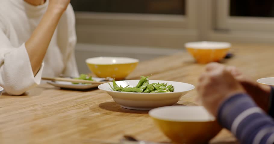Family dinner having appetizer, green soy bean dish at night