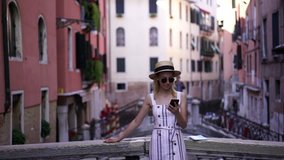 Slow motion effect of young beautiful female tourist recreating on italian bridge near canal in Venice watching video online from social networks with useful information for travellers