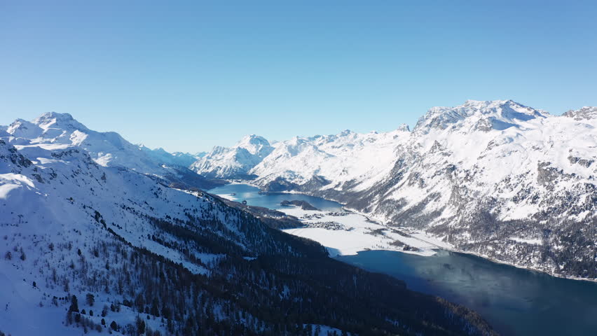 Aerial view of Swiss Alps mountains in winter, lakes Sils and Silvaplana, snow on slopes, sunny day with blue sky - ski resort St. Moritz, landscape panorama of Switzerland, Europe