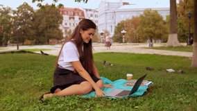 Young caucasian brunette with long hair sitting under the tree. happy student or businesswoman has break using webcam on laptop for video call in city park