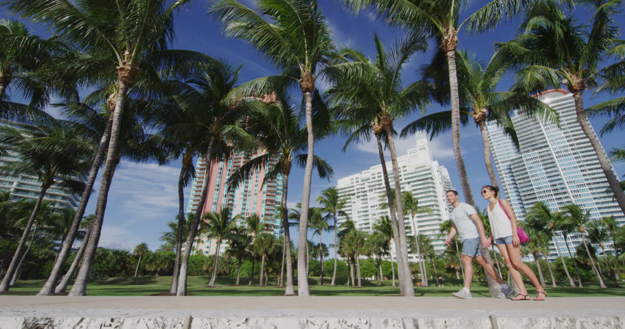 Miami people city lifetyle - young urban couple walking holding hands in Miami near South Beach. RED Cinema Camera in SLOW MOTION.