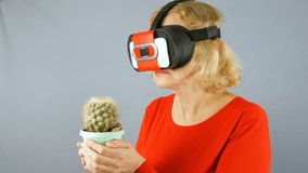 the beautiful girl in virtual reality glasses with cactus. Studio video. Imagination concept