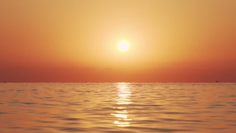 Sea surface small waves against of golden sunrise of sun slow motion. Large disk of sun rises above sea, solar path on water. Golden light of sea panorama. Relax. Nature