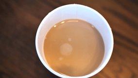 Clip taken at coffee shop cafe of a caucasian man stirring a cup with hot coffee or tea in it. Shot in 4k 60fps and slowed down to 50% on a 30fps timeline.
