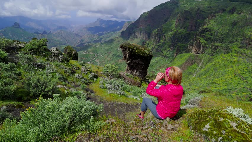 Young woman tourist sitting on cliff