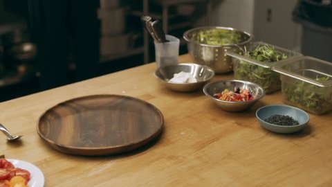 Work station with bowls of ingredients and vegetables on a long counter in industrial kitchen with soft lighting. Close up shot on 4k RED camera on a gimbal.