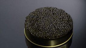 Black Caviar rotated background. High quality real natural sturgeon black caviar close-up, rotation. Delicatessen. Texture of expensive luxury caviar in tin can, on black. Seafood. 4K UHD video