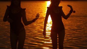 Video clip of three girls in bikinis dancing against the backdrop of the sunset on the beach