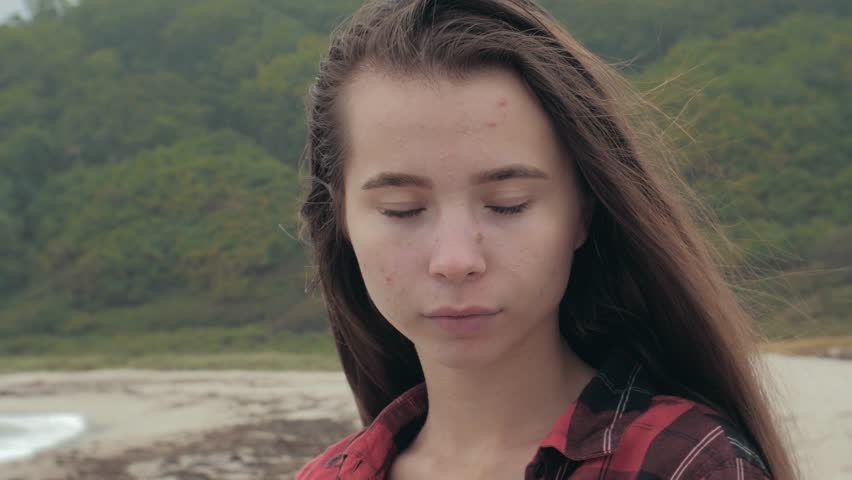 Close-up portrait of beautiful young european girl dressed in checkered shirt on tropical beach, sea on the background