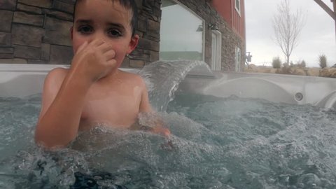 Two boys swimming in a hot tub at their house
