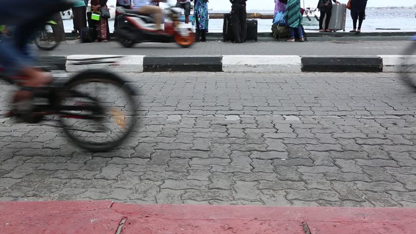 Busy traffic on city road of Male, Maldives. Cars, bicycles, motorcycles, people are in a hurry somewhere. Busy city life.