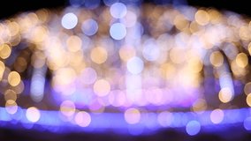 Beautiful colorful shiny bokeh background of holiday Christmas light glowing outdoors on winter cold snowy evening or night. Real time full hd video footage.