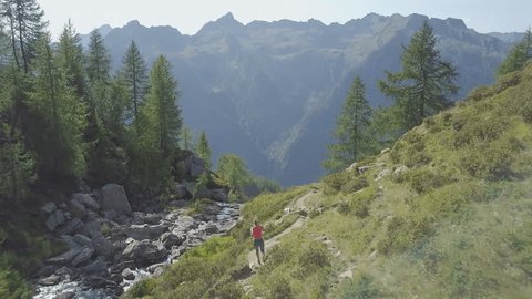 Drone shot of woman running on mountain trail in the Swiss Alps. Stunning shot taken with a drone of a woman trail running in the Alps. Sporty young woman practicing healthy lifestyle. Aerial view