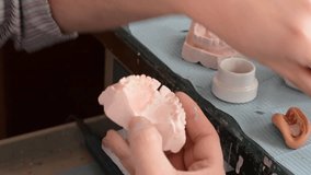 Dental technician works a dental prosthesis with precision instruments and wax. HD video