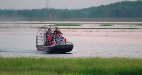 ORLANDO, FLORIDA circa Dec 2017 - An airboat carries tourists through a central Florida swamp and grassy wetlands in search of wildlife at sunset.