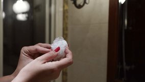 Woman unwrapping new single use plastic waterproof shower cap while standing in bathroom of hotel resort. Real time 4k video footage.