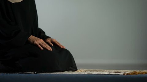 Young female in hijab praying on mat, asking god forgiveness, religious ritual