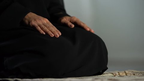 Woman in traditional black hijab kneeling on prayer mat mosque, islamic culture