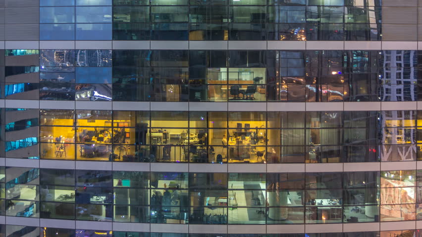 Glowing windows in multistory modern glass and metal office building light up at night timelapse. Workers in a box. Office building illuminated at night. Pan up Royalty-Free Stock Footage #1021901068