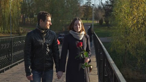 4K 60p Happy Couple On The Bridge In City Park. Romantic Dating. Joyful Man And Woman Hold Hands. Autumn Sunny Day