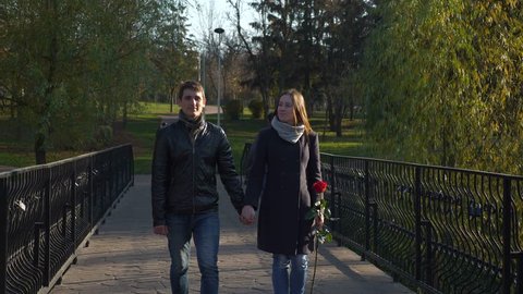 4K 60p Happy Couple On The Bridge In City Park. Romantic Dating. Joyful Man And Woman Hold Hands. Autumn Sunny Day