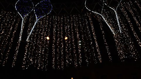 Bottom view of the bright Christmas garlands in the night city
