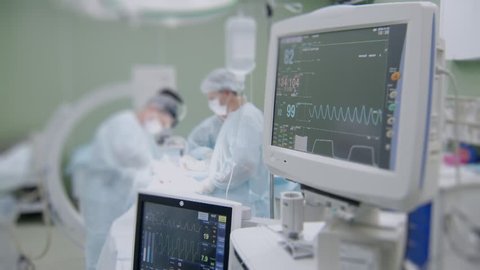 monitors of modern medical equipment with life parameters of patient, surgeons are working